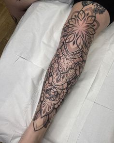 a person laying on a bed with a tattoo on their arm and leg that is covered in black ink