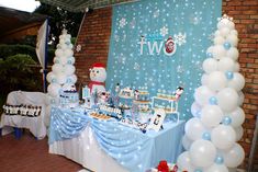 the table is set up with balloons, cake and desserts for a winter themed party