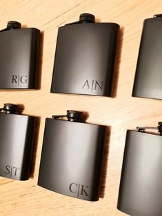 six black flasks sitting on top of a wooden table