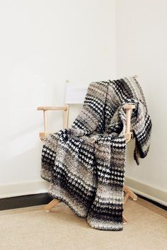 a chair with a blanket on top of it next to a white wall and floor