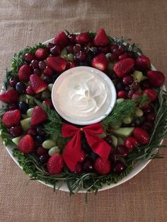 a platter filled with fruit and dip on top of a brown cloth covered table