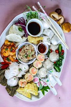 a white plate topped with different types of food next to chopsticks and sauce