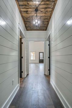 an empty hallway with white walls and wood ceiling