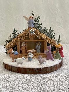 a nativity scene with figurines on top of a tree stump in the snow