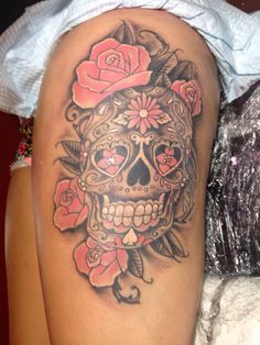 a woman's thigh with a skull and roses tattoo on it