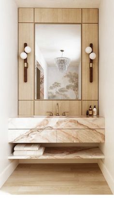 a bathroom vanity with marble counter top and mirror above it, along with two wall sconces