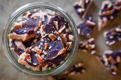 a jar filled with chocolate and nuts on top of a wooden table next to other pieces of food