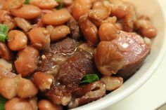 a white bowl filled with beans and meat