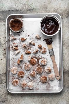 a tray filled with pastries covered in powdered sugar next to a cup of chocolate