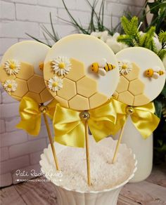 cake pops decorated with bees and daisies on top of a white cupcake stand