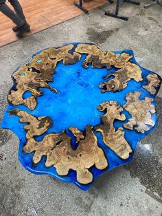 a blue and gold table sitting on top of a cement floor next to a person