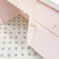 a white dresser sitting next to a bathroom sink under a window with scalloped trim