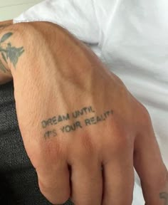 a man with a tattoo on his left hand and the words dream until it's your reality