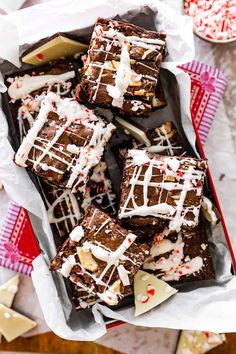 a tray filled with brownies covered in white icing and peppermint sprinkles