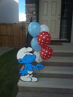 a bunch of balloons that are sitting on the steps in front of a house with a cartoon character