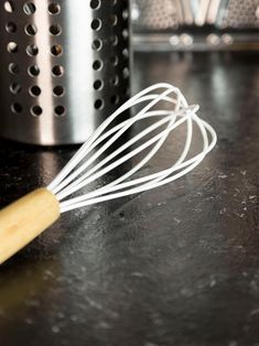 a whisk sitting on top of a counter next to a pot