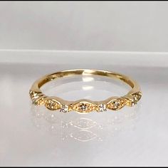 a yellow gold ring with three diamonds on the side, sitting on a white surface