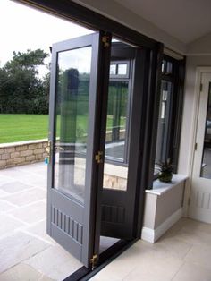 an open door leading to a patio with potted plants on the side and grass in the background