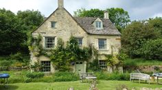 an old stone house surrounded by greenery and flowers