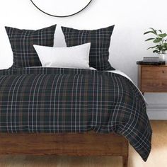 a bed with black and white plaid comforter in a bedroom next to a clock