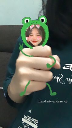 a woman holding up a frog shaped photo