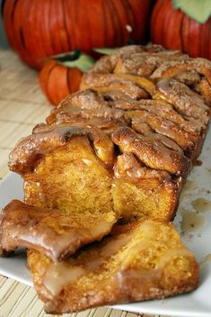 some cinnamon rolls on a white plate with pumpkins in the backgroung