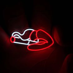 a red neon sign with a person laying on it's back in the dark