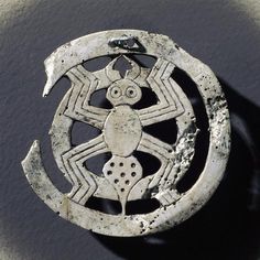 an old silver brooch with a spider on it's back and some holes in the middle