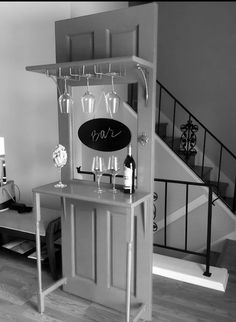 a black and white photo of a bar with wine glasses on the counter next to stairs