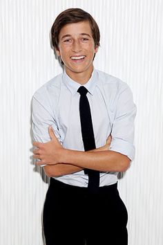 a young man in a dress shirt and tie posing with his arms crossed