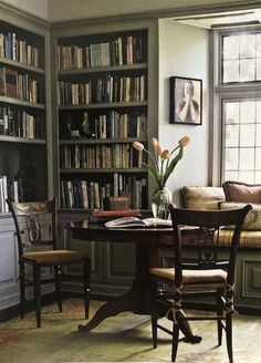 a living room filled with furniture and bookshelves next to a table covered in flowers