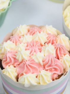 cupcakes with pink and white frosting in striped containers