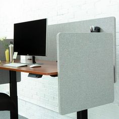 an office cubicle with two computer screens on it