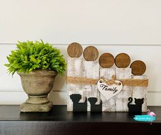 a potted plant sitting on top of a wooden shelf next to a family sign