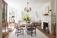 a living room with a table and chairs in front of a fire place next to a fireplace