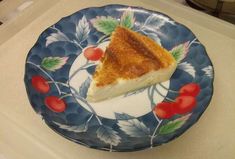 a piece of pie sitting on top of a blue and white plate with cherries