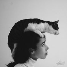 a black and white photo of a cat sitting on top of a woman's head