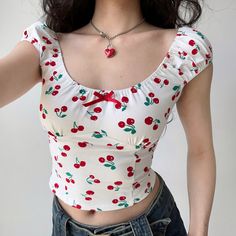 A thin, light-skinned woman's torso. She is wearing a white blouse with small red cherries printed on it. At the top of the blouse is a small red bow. She wears a red, heart-shaped lock necklace and dark jeans. The ends of her dark brown, wavy hair are visible. Fresh Cherry, Bodycon Dresses Casual, White Short Dress, Workwear Fashion, Cherry Print, Crop Top Blouse, Spice Girls, Suit Fashion, Girls Jacket