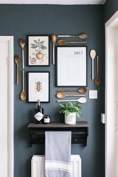 a kitchen wall with spoons, utensils and framed pictures on the wall