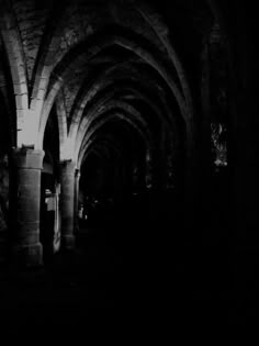 an empty cathedral in the dark with light coming from it's windows and arches