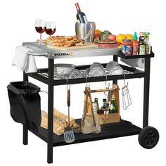 an outdoor bbq grill with wine glasses and food on the counter top, including breads, cheeses, tomatoes, and other foods