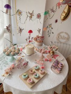 a table topped with cakes and cupcakes on top of a white table cloth