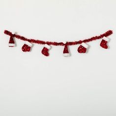 a red string with christmas decorations hanging from it's sides on a white wall