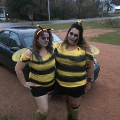 two women dressed in bee costumes standing next to a car