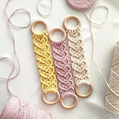 three crocheted yarns and two wooden scissors on a white surface next to spools of thread