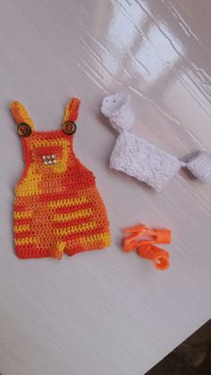 a crocheted baby's outfit next to scissors on a table