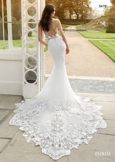 a woman in a white wedding dress standing by an open doorway with her back to the camera