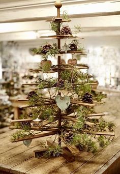 a wooden table topped with a christmas tree made out of wood sticks and pine cones