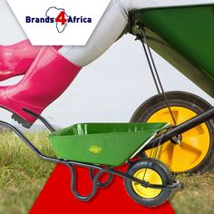 a woman in pink boots pulling a green wheelbarrow