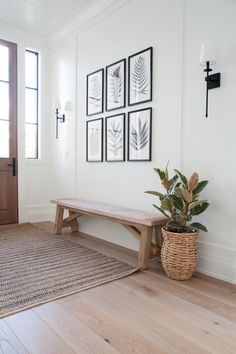 a wooden bench sitting next to a plant on top of a rug in front of a door